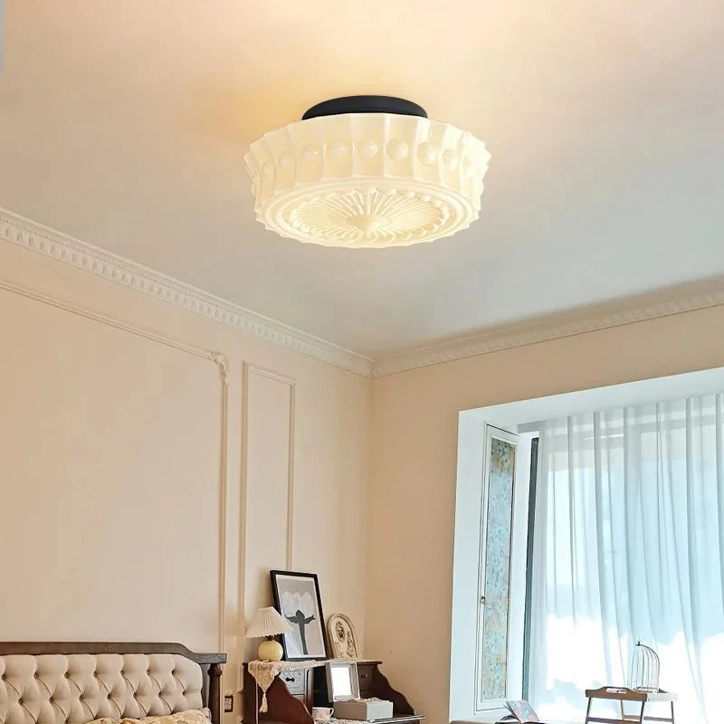 A corner view of a room showing the white frosted glass drum semi-flush ceiling light.