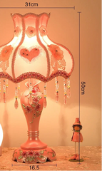 Decorative table lamp with floral design and remote control on a wooden surface.