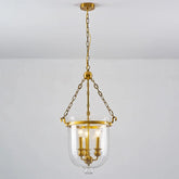 Polished copper and clear glass drum pendant light hanging from a chain against a white ceiling