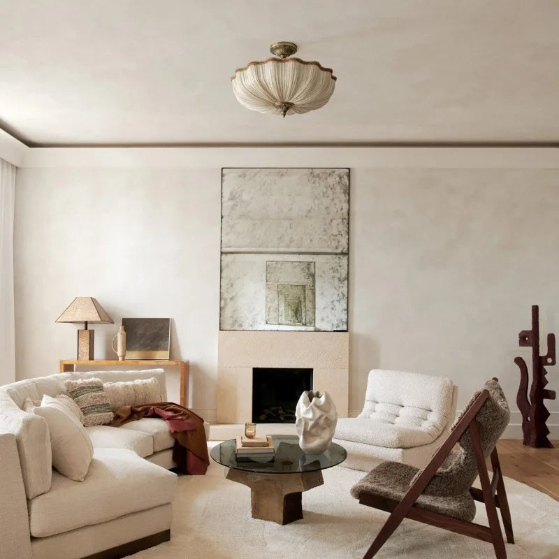 A living room interior with a beige fabric pleated semi-flush ceiling light installed