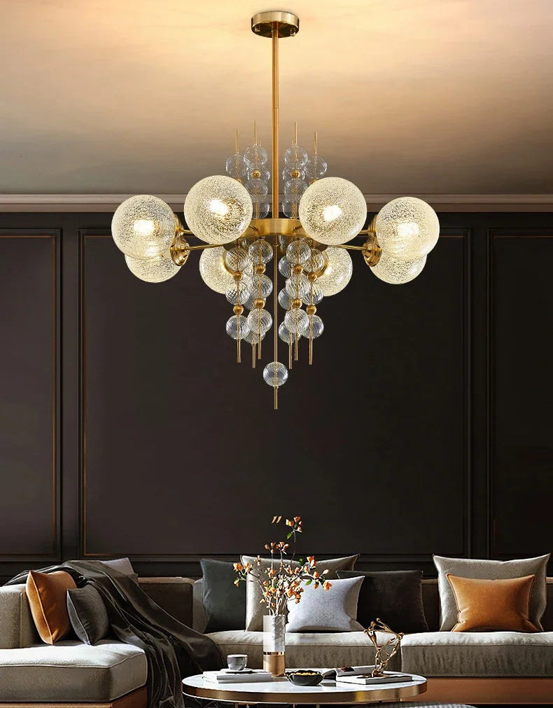 Chandelier hanging above a living room with dark walls and a gray sofa.