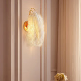 Wall-mounted light fixture with feather design on a striped wall.
