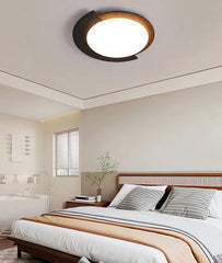 Ceiling light fixture in a bedroom setting with a bed and window in the background.