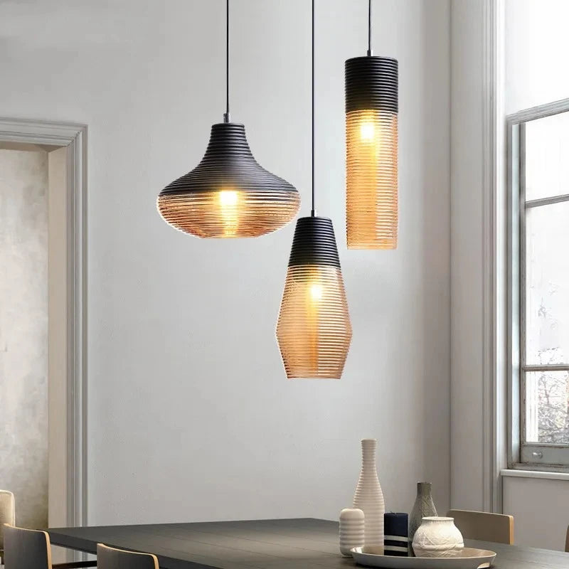 Three pendant lights with ribbed glass shades hanging in a well-lit room with a window.
