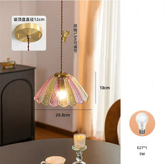 Decorative pendant light with floral design, placed on a table with a candle and cup in a room setting.