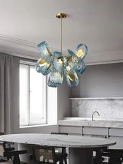 Modern chandelier hanging above a kitchen counter with a marble table and window in the background.