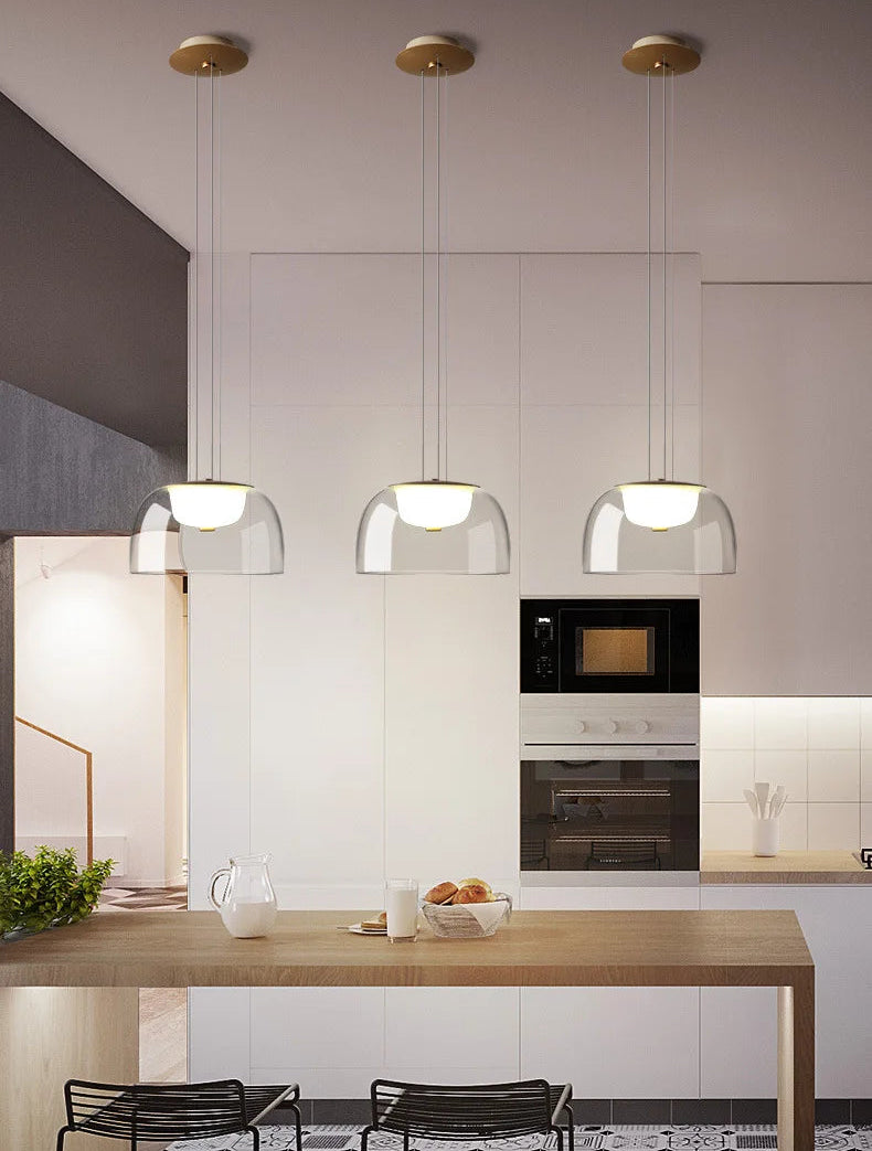 Modern kitchen with pendant lights, wooden island, and black chairs.