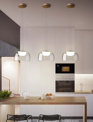 Modern kitchen with pendant lights, wooden island, and black chairs.