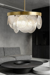 A modern gold chandelier with cascading clear glass discs hanging above a coffee table in a living room.