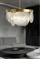 A modern gold chandelier with cascading clear glass discs hanging above a coffee table in a living room.