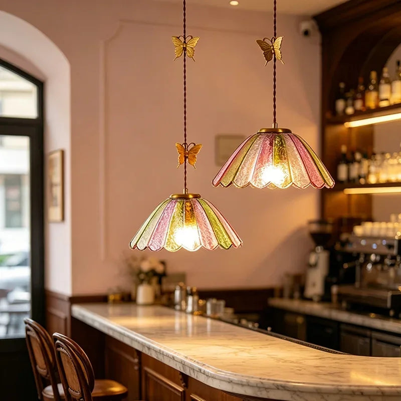 Colored glass butterfly pendant lights displayed in a bar setting above a marble countertop.