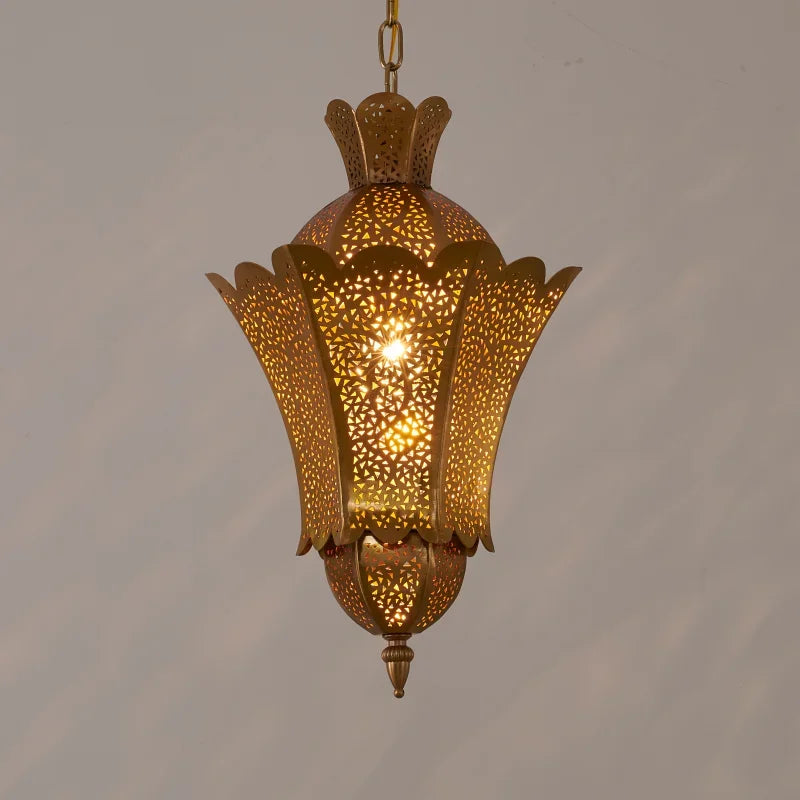 A gold hollow carved floral pendant light casting intricate shadows on a wall.