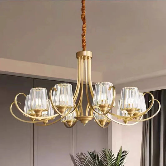 Close-up view of a polished gold chandelier with faceted crystal droplets and floral accents hanging in a modern room.