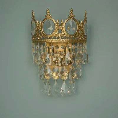 Decorative wall sconce with gold frame and crystal accents on a gray background
