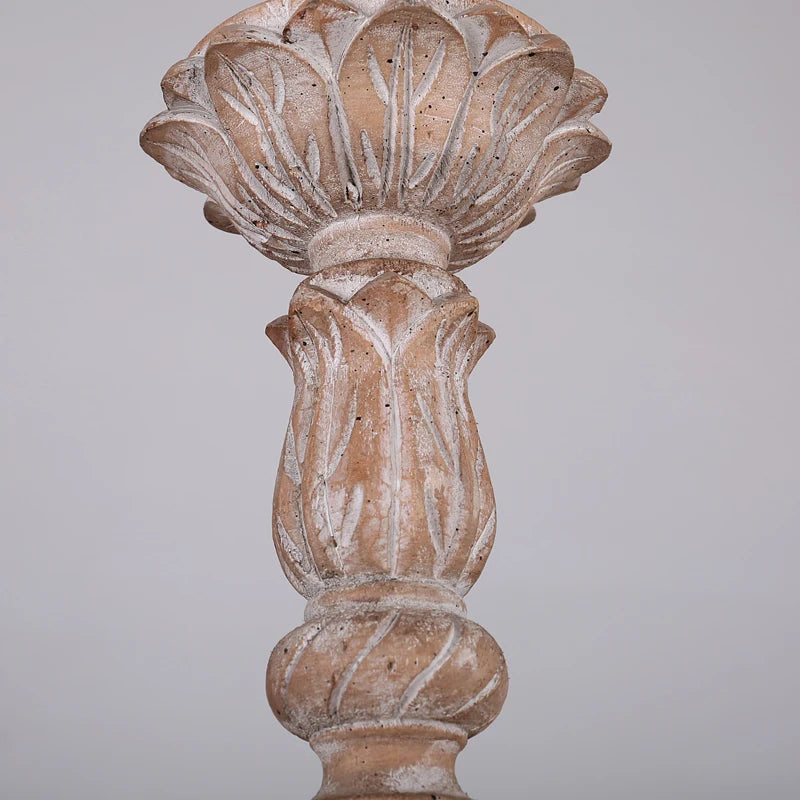 Top detail of the distressed wood chandelier, showing the carved floral element on the central column and the chain for hanging.