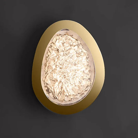 Gold textured resin egg-shaped wall sconce mounted on a dark gray wall, lit from within.