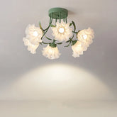 Green semi-flush mount ceiling light with five white frosted glass flower bud shades and green metal leaf accents, casting a warm glow on a white ceiling.