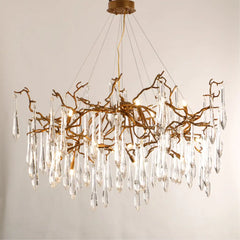 Chandelier with gold branches and clear crystal elements on a neutral background