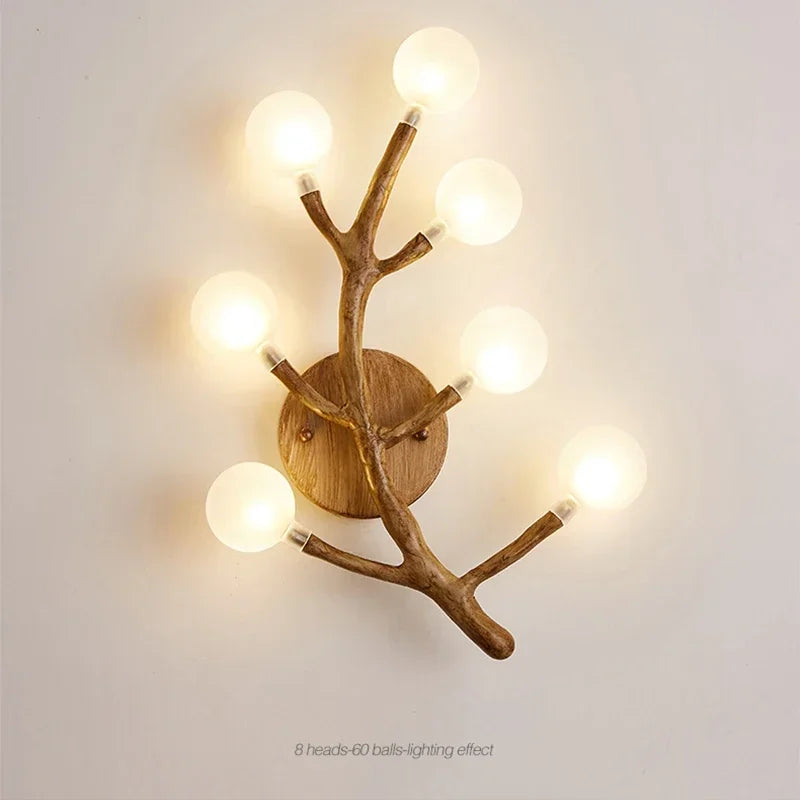 Wall-mounted light fixture with branch-like design on a plain wall.