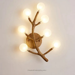 Wall-mounted light fixture with branch-like design on a plain wall.