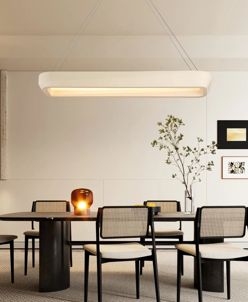Modern dining room with a table and chairs, featuring a pendant light fixture.