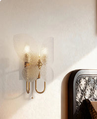 Decorative wall sconce with a textured glass shade on a neutral wall.