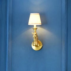 Gold wall sconce with a horse head design on a blue wall