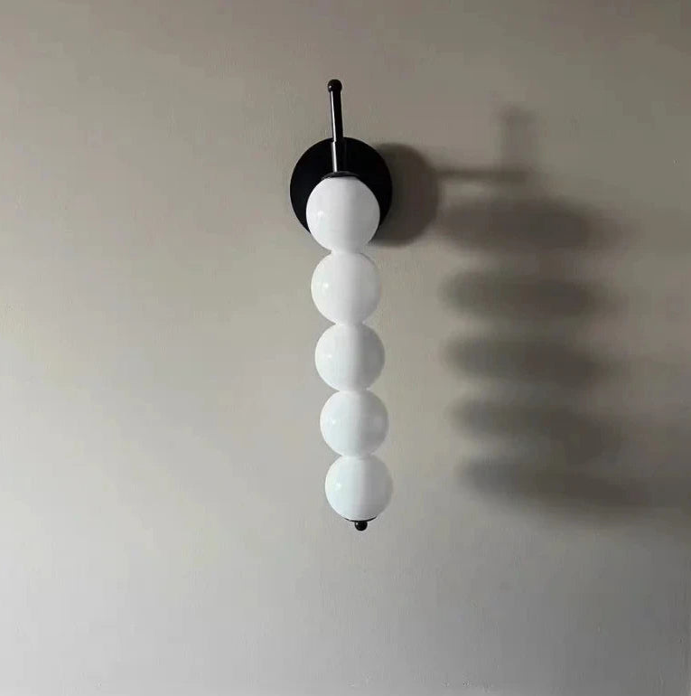 Wall-mounted light fixture with white spherical shades on a plain wall.