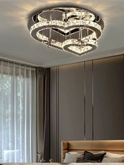 A dimly lit bedroom featuring a heart-shaped crystal chandelier as the main light source, casting a warm glow.