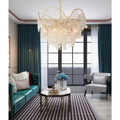 A modern living room featuring a gold cascading crystal chandelier hanging above a glass coffee table.