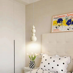 Cream gourd-shaped pendant light hanging over a bed with a framed bicycle print on the wall.