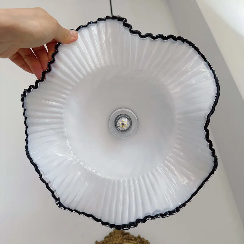 Round white light fixture with black rim held by a hand against a neutral background