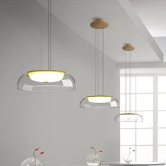Three modern pendant lights hanging in a room with a window in the background.