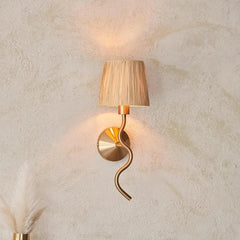 Decorative wall lamp with a gold spiral design on a textured beige wall.