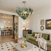 A modern chandelier with layered green and blue glass discs hanging from a chrome frame, illuminating a contemporary living room.