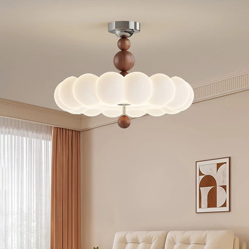 A room with a pink cloud flush mount ceiling light, a bed with pillows, and light beige curtains.
