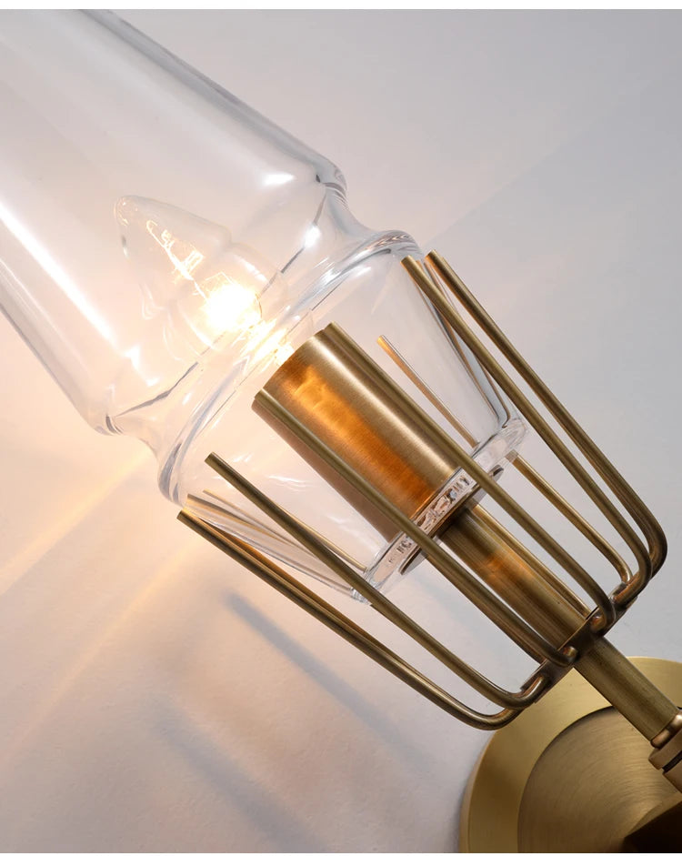 Gold wall sconce with clear glass shade on a white background