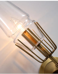 Gold wall sconce with clear glass shade on a white background