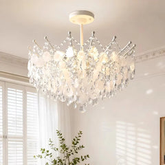 The gold crystal chandelier illuminated in a room setting, casting light patterns on the ceiling and walls.