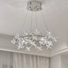 A detailed view of a chrome ring chandelier featuring numerous clear crystal floral accents, illuminated and casting light patterns.