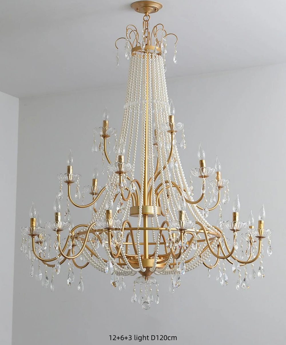 Gold chandelier with crystal accents on a gray wall background