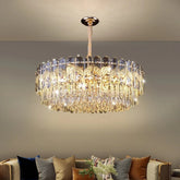 A luxurious tiered gold crystal chandelier with cascading teardrop crystals, illuminating a modern living room.