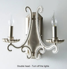Decorative wall sconce with two candle-style lights on a plain background
