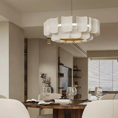 A dining room setting featuring a gold tiered acrylic wave chandelier