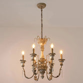 A distressed gold and white floral candelabra chandelier with crystal accents hanging from a chain against a plain background.