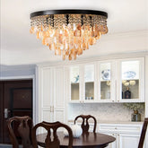 A gold and shell semi-flush mount ceiling light with multiple tiers of teardrop shapes hanging from a circular base, illuminating a dining room.