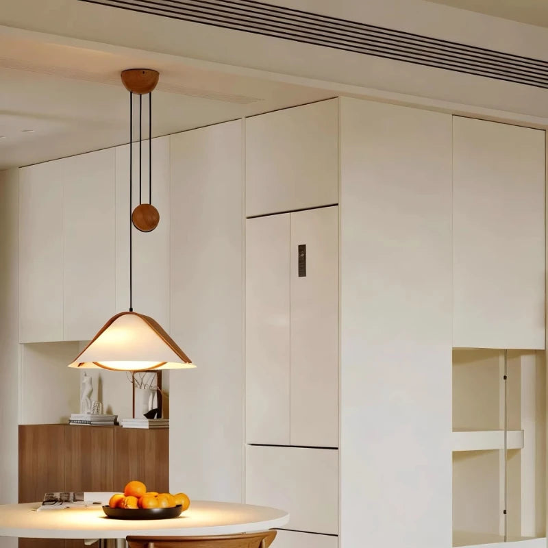 Fabric cone pendant light with wood accents hanging in a kitchen area near a refrigerator.