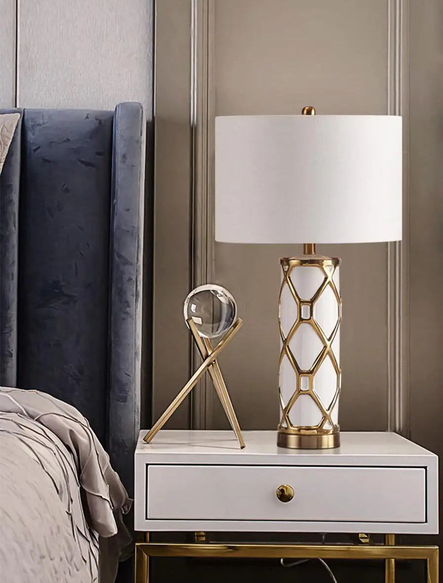 Decorative lamp on a nightstand next to a bed with a gray headboard.
