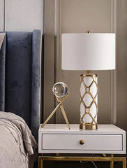 Decorative lamp on a nightstand next to a bed with a gray headboard.