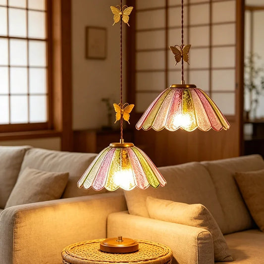 Two scalloped colored glass pendant lights with butterfly accents hanging above a sofa.